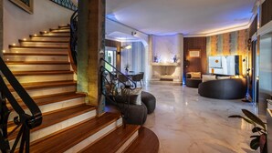 A modern interior with a wooden staircase, a fireplace, a seating area, and a television.