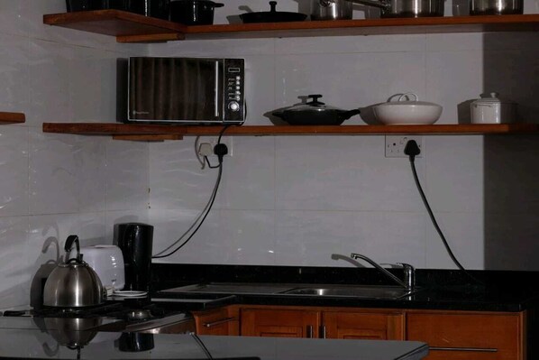 A kitchen with a microwave, kettle, toaster, and a sink. - Philadelphia Executive Suite (Harare)