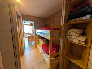 A wooden bunk bed room with a desk and chair, wooden shelves, and a view through an open door. - Renovated studio, slopes view - 4 guests (Montgenèvre)