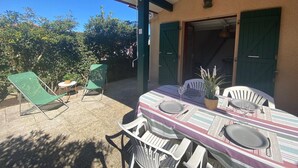Eine Terrasse mit Tisch für zwei Personen, zwei Stühlen, einem kleinen Tisch und einem Blumentopf.