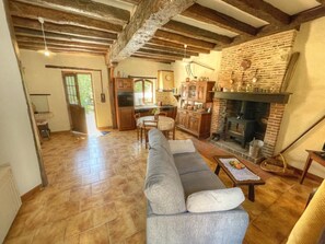 Ein Wohnzimmer mit Sofa, Kamin, Küche und Holzbalken.