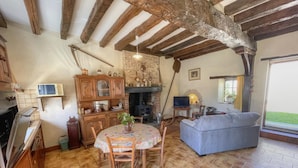 A rustic kitchen with a dining table, wooden cabinets, and a fireplace. - Charming cottage near Loire Castles (La Chapelle-Montmartin)