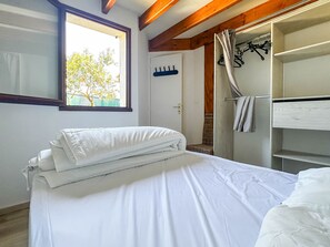 Une chambre à coucher comprenant un lit, une fenêtre, une armoire et une porte donnant sur une salle de bain.