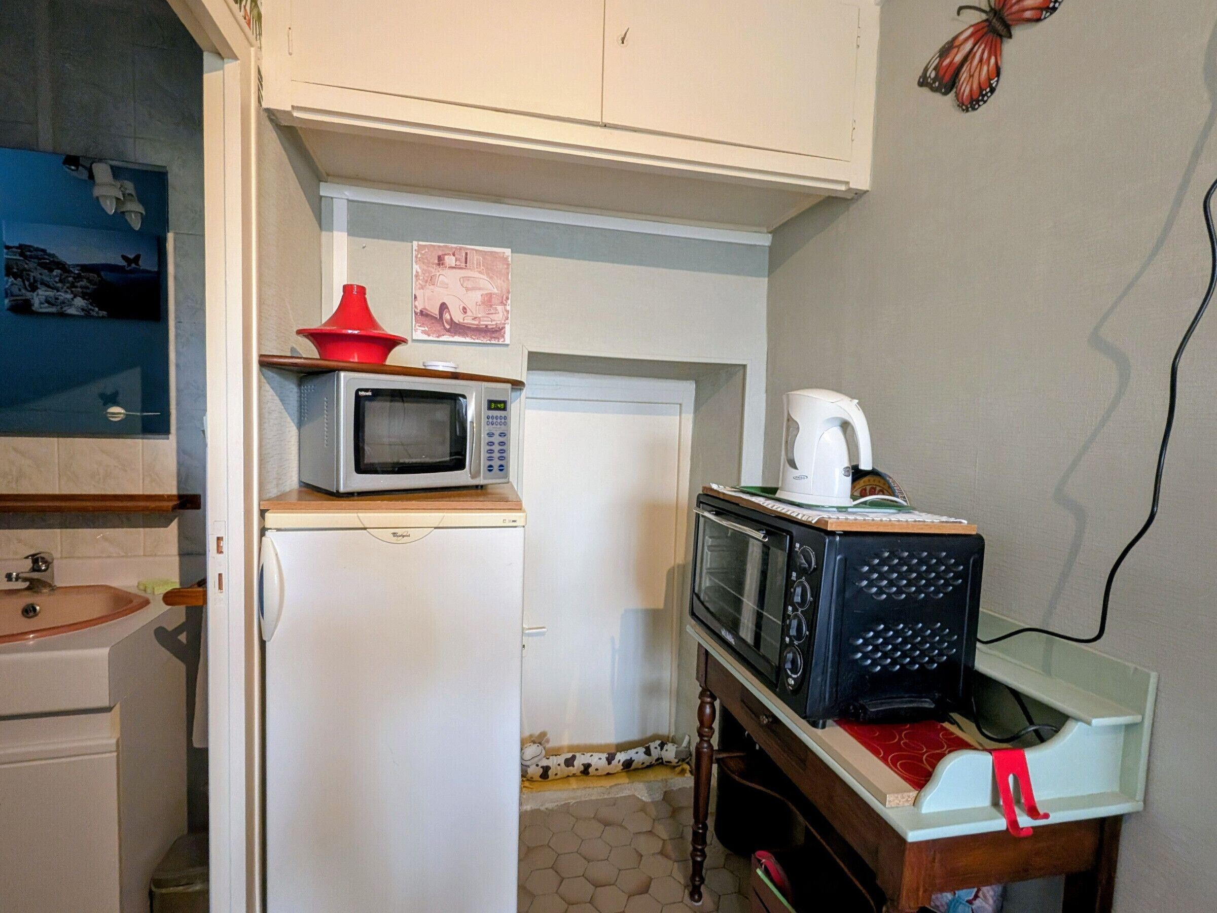A compact kitchen with a microwave, toaster, and coffee maker on a countertop.