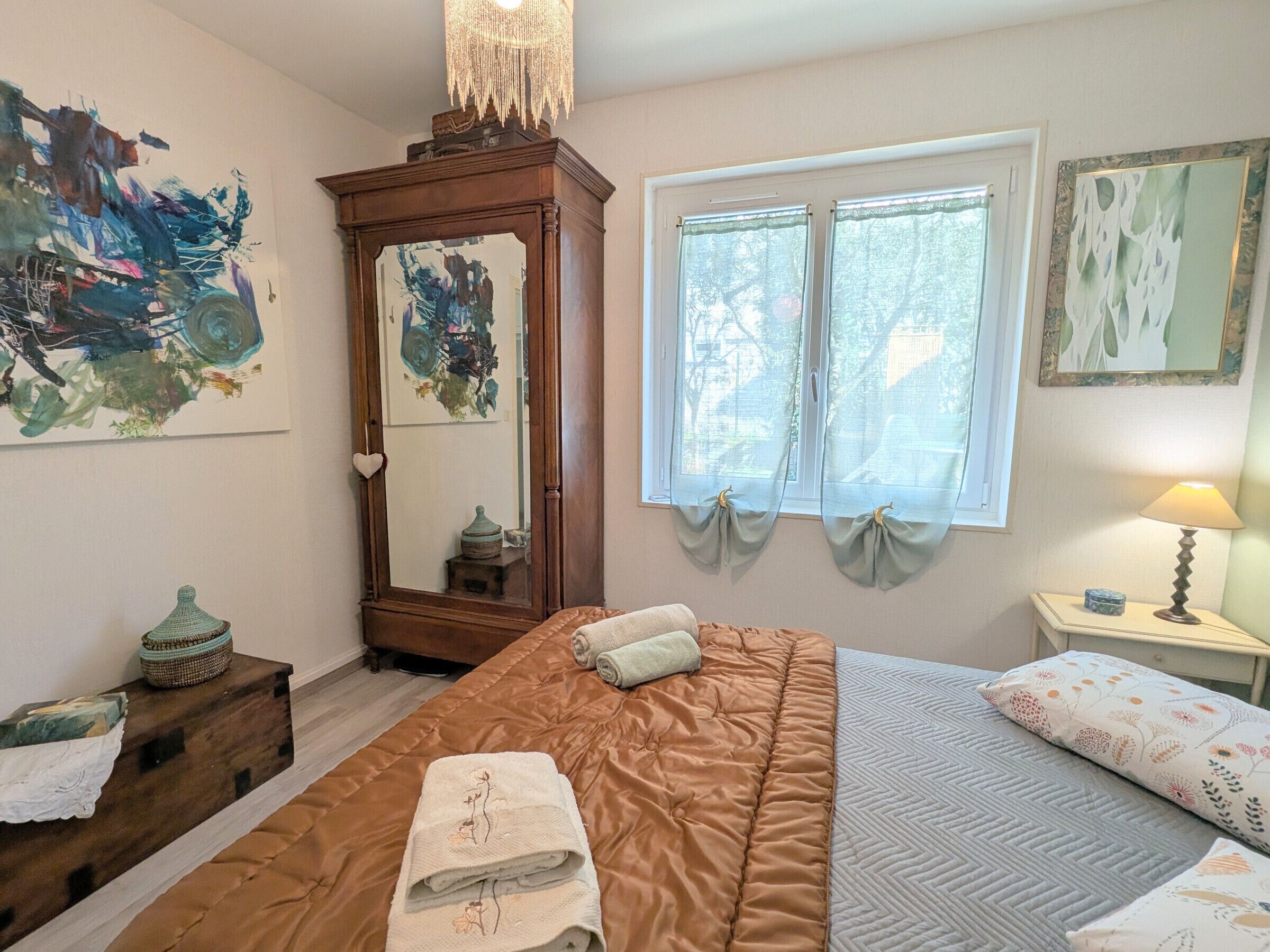 A bedroom with a large bed, a dresser, a mirror, and artwork on the walls.
