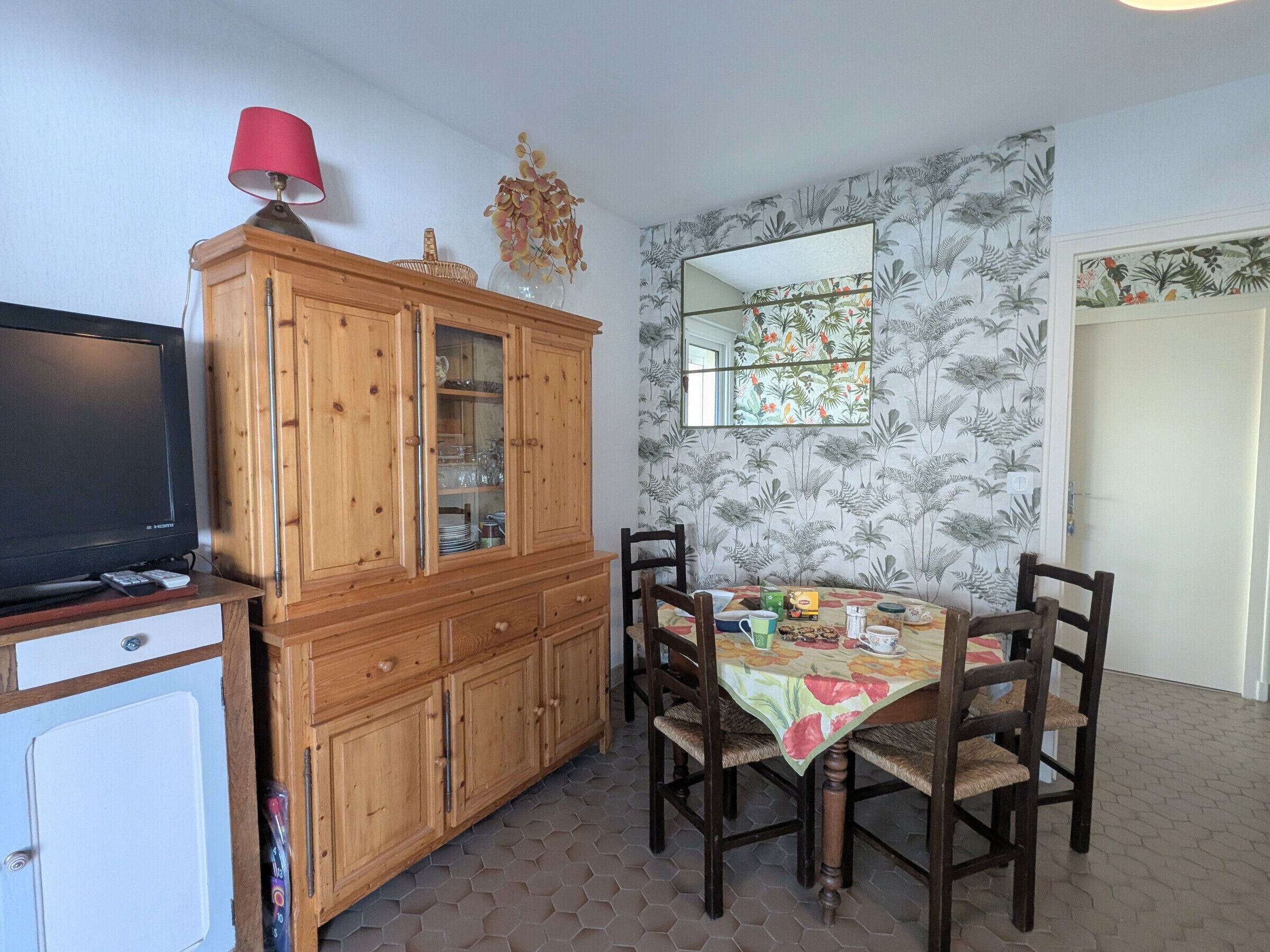 A dining area with a wooden cabinet, a television, and a table with chairs.