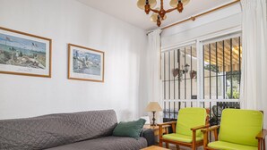 Un salon comprenant un canapé, deux fauteuils, une table en bois et deux tableaux encadrés accrochés au mur.