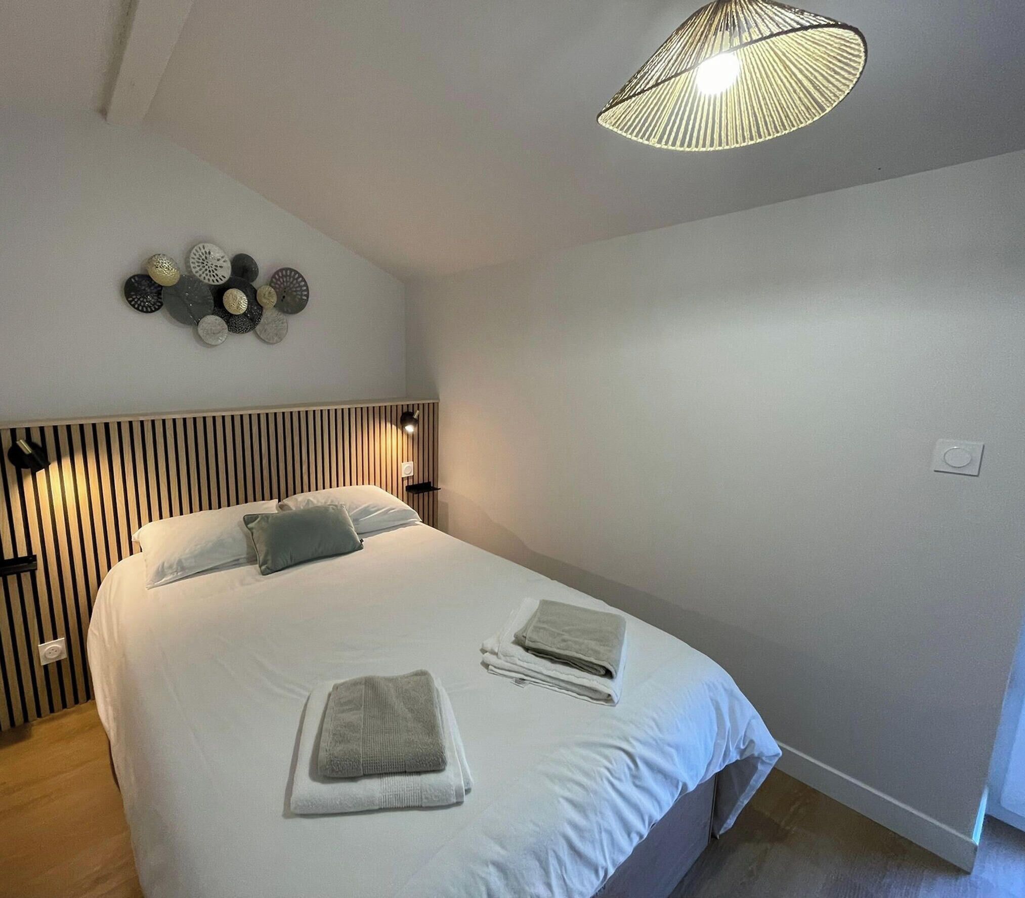 A bedroom with a bed, a wall-mounted light fixture, and a ceiling light.