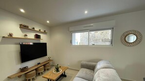 A living room with a flat-screen TV, wooden shelves, a sofa, a coffee table, and a window with a view. - House with AC and parking - 6 guests (Saint-Vincent-Sterlanges)