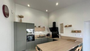 A modern kitchen with grey cabinets, a wooden countertop, a built-in oven, and a black range hood. - House with AC and parking - 6 guests (Saint-Vincent-Sterlanges)