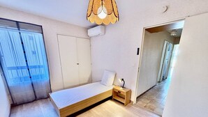 Makuuhuone, jossa on sänky, yöpöytä, lamppu, vaatekaappi ja ikkunasta avautuva näkymä.