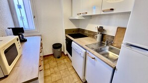 Kompakti keittiö, jossa on mikroaaltouuni, kahvinkeitin, pesuallas ja astianpesukone.