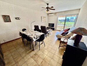 A dining area with a table set for four, a television, and a ceiling fan. - Air-conditioned apartment, pets OK, parking - 5 guests (Le Lavandou)
