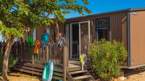 A wooden structure with a porch, steps, and a fenced area with inflatable toys. - Mobile home with AC - Pets OK - 6 guests (Frontignan)