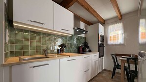 A modern kitchen with white cabinets, a green backsplash, and a wooden ceiling. - Charming house near the beach - 4 guests (Saint-Georges-d'Oléron)