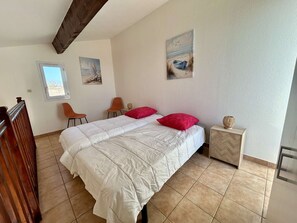 A bedroom with a bed, two chairs, a small table, and artwork on the walls. - Bright apartment near the beach - 4 guests (Cap d'Agde)