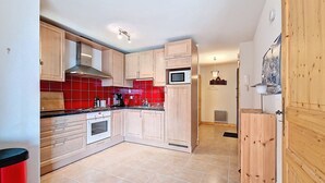 A kitchen with wooden cabinets, a microwave, and a stove. - Spacious duplex near Super Châtel (Châtel)