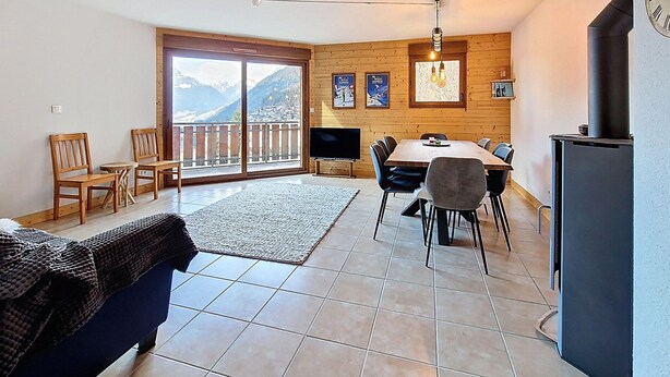 A modern living room with a dining area, large windows with a mountain view, a fireplace, and a television. - Spacious duplex near Super Châtel (Châtel)