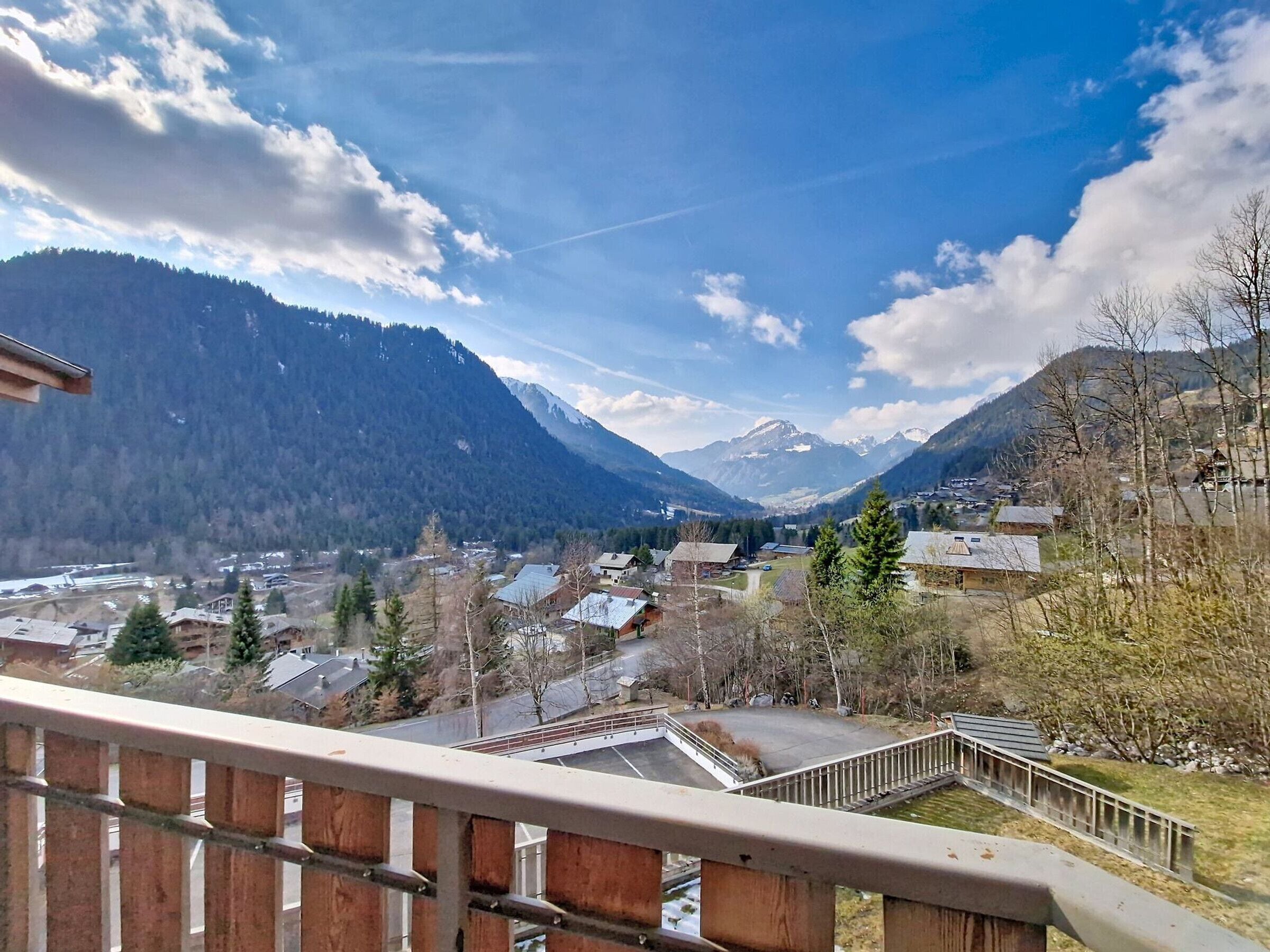 A mountainous landscape with a village, a bridge, and a clear sky.