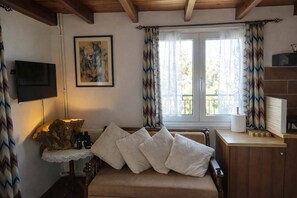 A cozy room with a bed, a television, a painting, and a window with curtains.