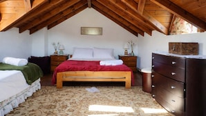 An attic bedroom with a wooden ceiling, a bed with a red blanket, a dresser, and a nightstand with a lamp. - Villa Dorothy - Mountain View Retreat Polydrosos (Delphi)
