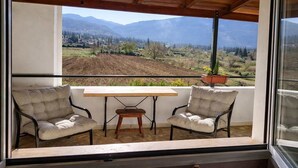 A balcony with two chairs, a small table, and a potted plant. - Villa Dorothy - Mountain View Retreat Polydrosos (Delphi)