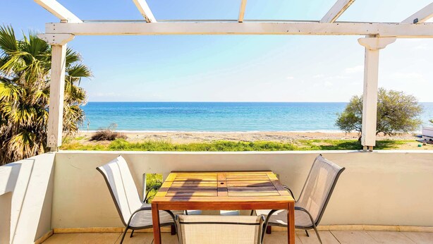 A covered patio with a table and chairs, overlooking a beach. - Beachfront Nest Memi Koroni-seaheaven House B1 (Pylos-Nestoras)