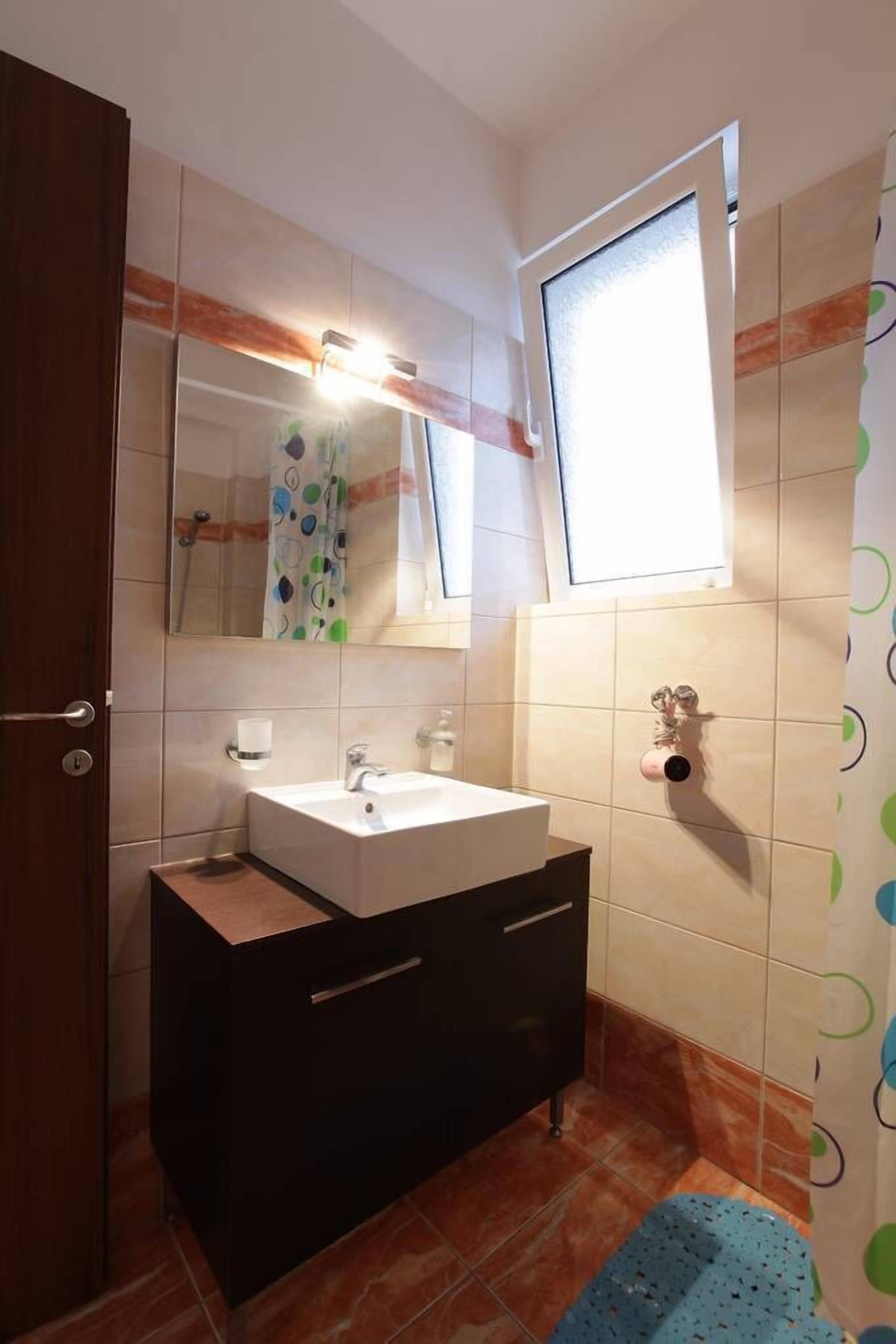 Un baño con lavamanos, espejo y ventana.
