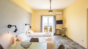 Hotellihuone, jossa on kaksi sänkyä, työpöytä, tuoli, televisio ja parveke, jolta on näkymä.