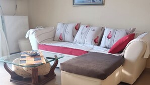 A living room with a sofa, ottoman, and a glass coffee table. - Bussiness Maisonette Getaway 5 min From the Beach (Kymi-Aliveri)