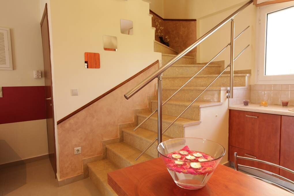 Eine Küche mit einem Holztisch, einer Glaskugel mit Kerzen und einer Treppe.