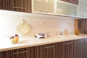 A kitchen with a white countertop, a fruit bowl, a coffee maker, and a sink. - Family Apartment Cozy Getaway 5 min From the Beach (Kymi-Aliveri)