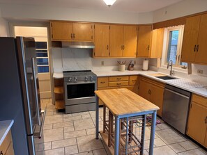 Eine moderne Küche mit Holzausstattung, einem Edelstahlkühlschrank, einem Einbauofen und einem Spülbecken.