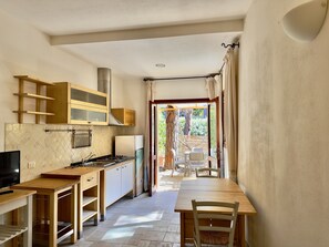 A compact kitchen with a dining area, a TV, and a view of the outdoors. - Residence Abbaechelu Santa Margherita Pula (Pula)