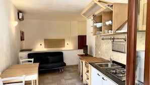 Una cocina compacta con comedor, un sofá y un televisor.