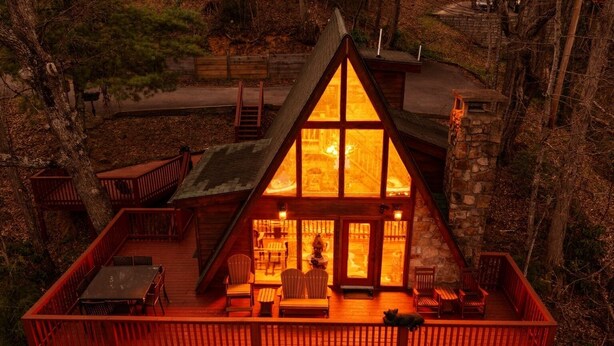 Une cabane dotée d’une terrasse en bois, d’une cheminée et d’un mur en pierre.