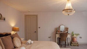 A bedroom with a bed, a desk, a chair, a chandelier, and a door. - Georgian Gem Penthouse in Bath Centre! (Bath)