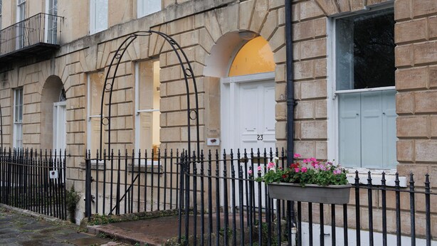 A building with multiple windows, a black metal fence, and a number '23' on the door. - Georgian Gem Penthouse in Bath Centre! (Bath)