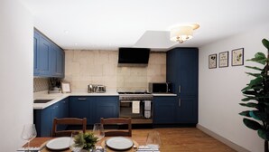 A modern kitchen with blue cabinets, a built-in oven, and a flat-screen TV. - Georgian Gem Penthouse in Bath Centre! (Bath)