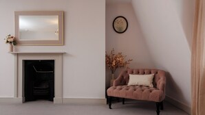 A room with a fireplace, a cushioned armchair, a mirror, and a framed picture on the wall. - Georgian Gem Penthouse in Bath Centre! (Bath)