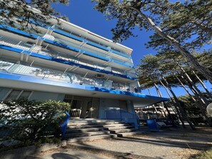 A multi-story building with balconies, a staircase, and trees. - Cozy Accommodation Just 250mt From the Beach (Lignano Sabbiadoro)