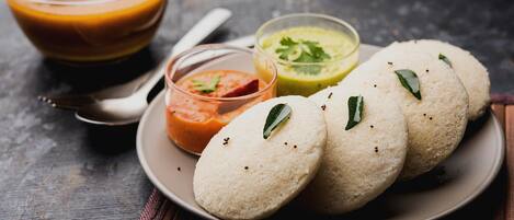 A plate with idlis and three different chutneys.
