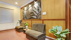 A reception area with a sofa, armchair, and a potted plant. - Deluxe Skanda Shelters (Bengaluru)