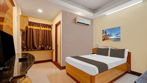 A hotel room with a bed, a desk, an air conditioner, and a painting on the wall. - Deluxe Skanda Shelters (Bengaluru)
