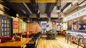 Un restaurante con paredes de ladrillo, mesas de madera y asientos rojos.