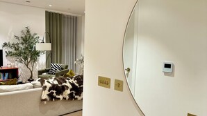 Un salon moderne avec un canapé, une lampe, une plante et un grand miroir.