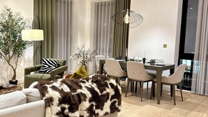 Un salon moderne comprenant un canapé, une table à manger, des chaises et un luminaire suspendu.