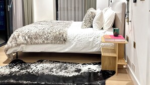 Une chambre à coucher moderne avec un lit, une table de chevet, une lampe et un grand tapis.