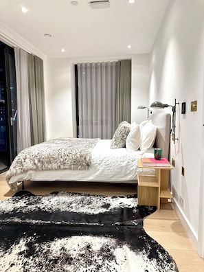 A modern bedroom with a bed, bedside table, lamp, and a large rug. - Kings Cross Exclusive residence - 3BR (London)