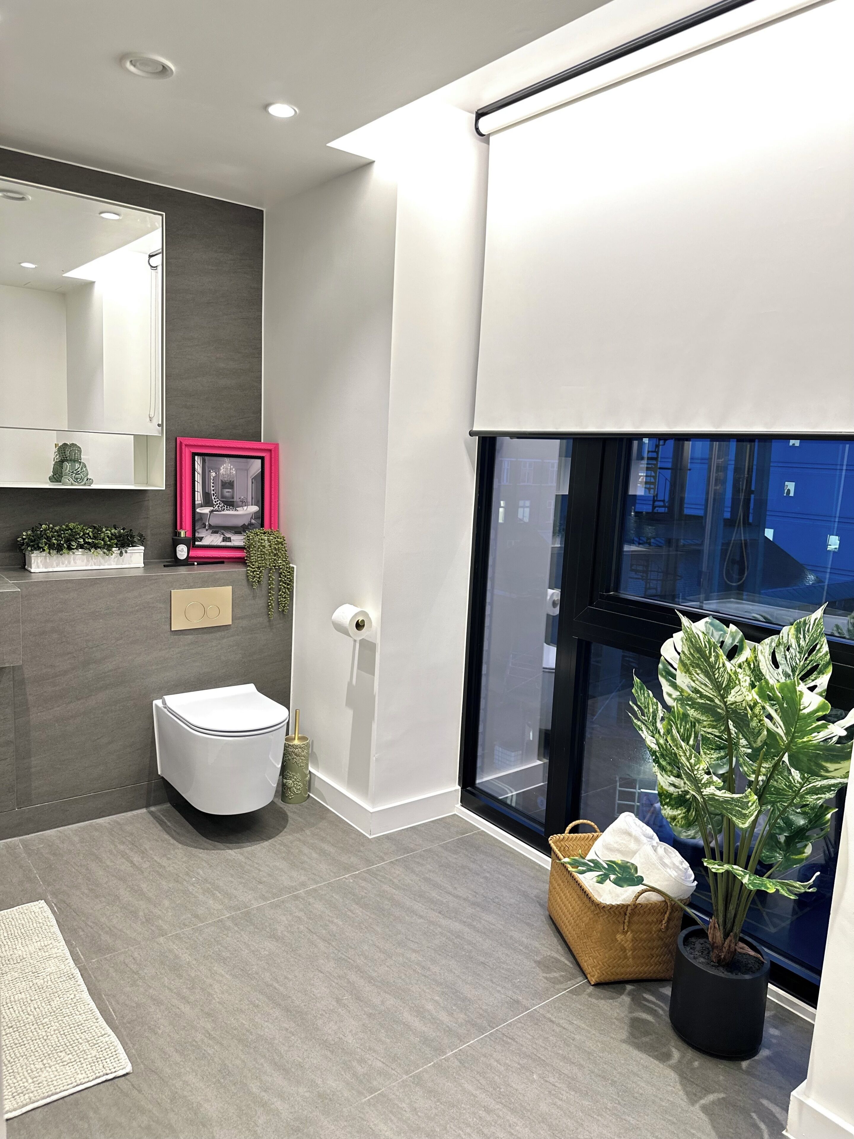 A modern bathroom with a toilet, sink, mirror, and a large window.